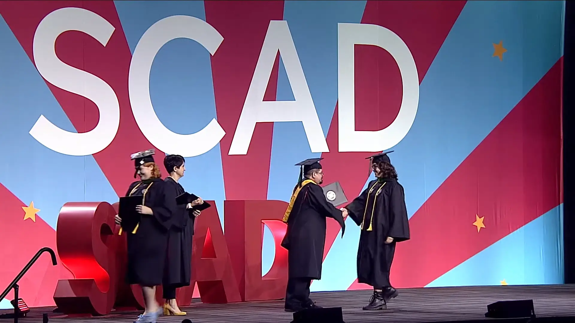 Alicia Drinkwater shaking hands with another design industry professional on stage at SCAD in Georgia.